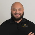 MAn with bear smiling at camera with black polo shirt