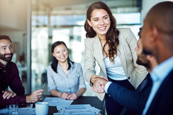 woman shakes hands and smiles after an insurance claim settlement