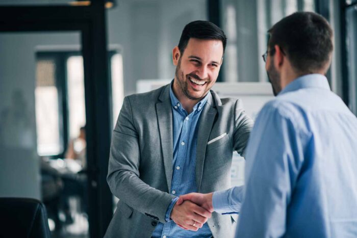 two men shake hands after a successful insurance claim resolution